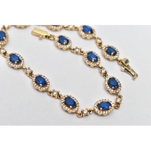 67 - A YELLOW METAL GEM SET BRACELET, comprised of twelve oval cut synthetic blue spinel, each set with a... 