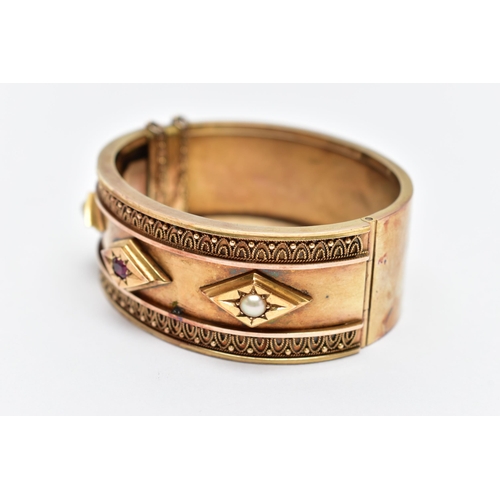 47 - A LATE VICTORIAN GEM SET HINGED BANGLE CIRCA 1890, set with a cushion shape ruby and two split pearl... 