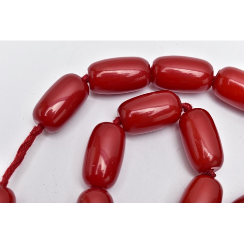 9 - A CHERRY AMBER BAKELITE BEAD NECKLACE, designed with a single row of thirty-five barrel shape beads,... 