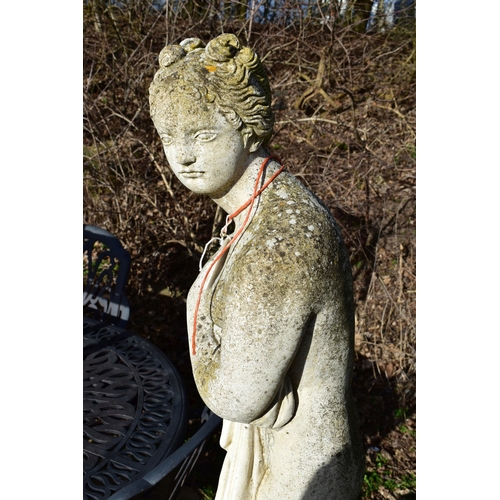 906 - A WEATHERED COMPOSITE GARDEN FIGURE, of a scantily clad lady in flowing robes, on a separate plinth,... 