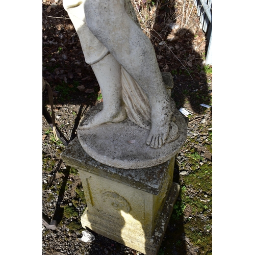 906 - A WEATHERED COMPOSITE GARDEN FIGURE, of a scantily clad lady in flowing robes, on a separate plinth,... 