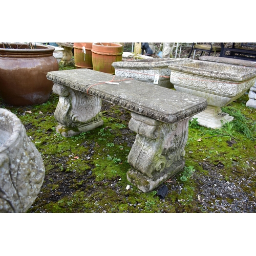 930 - A WEATHERED COMPOSITE GARDEN BENCH, on a twin scrolled base, length 97cm x depth 37cm x height 40cm ... 