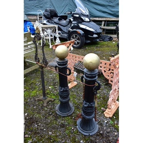 950 - A PAIR OF CAST IRON PILLAR POSTS, with a gold painted finial, height 82cm with rusted chains, along ... 