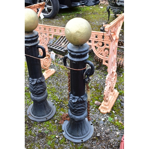 950 - A PAIR OF CAST IRON PILLAR POSTS, with a gold painted finial, height 82cm with rusted chains, along ... 