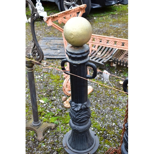 950 - A PAIR OF CAST IRON PILLAR POSTS, with a gold painted finial, height 82cm with rusted chains, along ... 