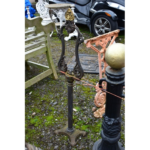 950 - A PAIR OF CAST IRON PILLAR POSTS, with a gold painted finial, height 82cm with rusted chains, along ... 