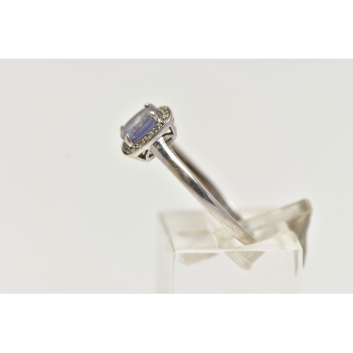 56 - A WHITE METAL IOLITE AND DIAMOND CLUSTER RING, designed with a square cut iolite within a surround o... 