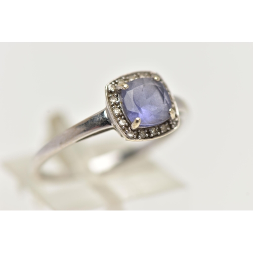 56 - A WHITE METAL IOLITE AND DIAMOND CLUSTER RING, designed with a square cut iolite within a surround o... 