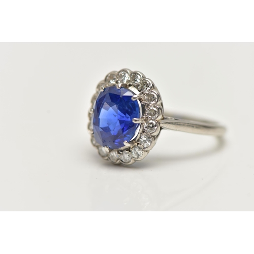 6 - A SAPPHIRE AND DIAMOND CLUSTER RING, set with a mixed cut, cushion sapphire, measuring approximately... 