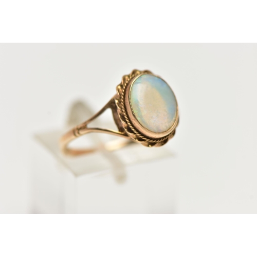 60 - A 9CT GOLD OPAL RING, designed with an opal cabochon, in a milgrain collet setting, to a rope twist ... 