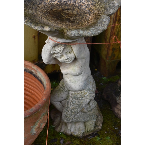 1015 - A MODERN COMPOSITE BIRD BATH in the form of a small child seated on a tree stump holding a flower sh... 