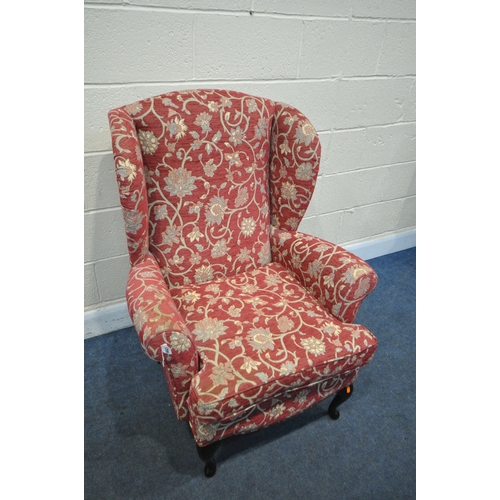 1299 - A RED FLORAL PATTERN WING BACK ARMCHAIR, on ebonised cabriole legs (condition:-slightly dirty armres... 