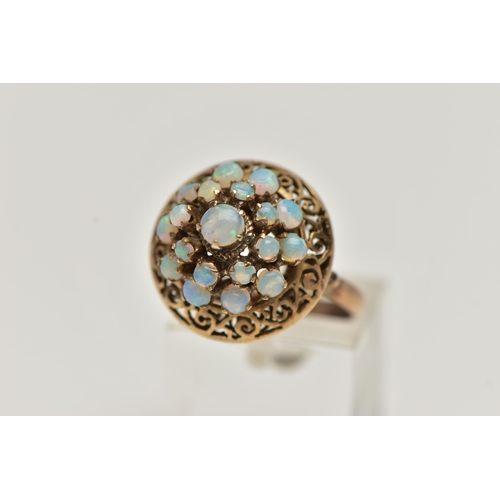 25 - A YELLOW METAL OPAL RING, tiered ring set with nineteen opal cabochons, to the openwork scroll surro... 