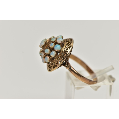 25 - A YELLOW METAL OPAL RING, tiered ring set with nineteen opal cabochons, to the openwork scroll surro... 