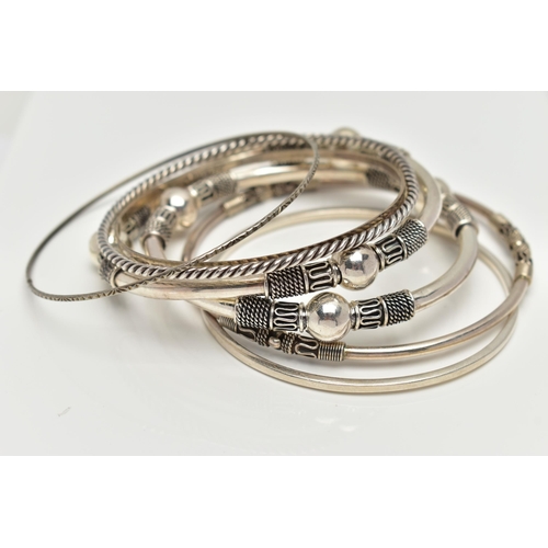 82 - SEVEN WHITE METAL BANGLES, to include two with bead and rope twist patterns, unmarked, a thin bangle... 