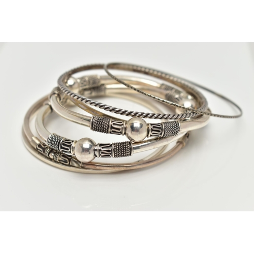 82 - SEVEN WHITE METAL BANGLES, to include two with bead and rope twist patterns, unmarked, a thin bangle... 