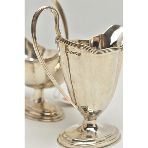 232 - AN EDWARDIAN MATCHED MILK JUG AND SWING HANDLED SUGAR BASKET OF PANELLED OVAL FORM, reeded rims, sho... 