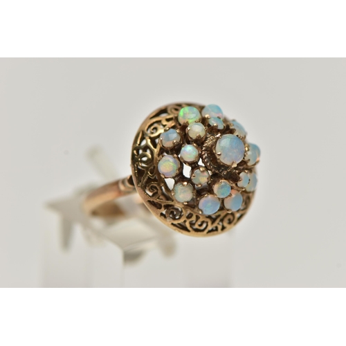 25 - A YELLOW METAL OPAL RING, tiered ring set with nineteen opal cabochons, to the openwork scroll surro... 