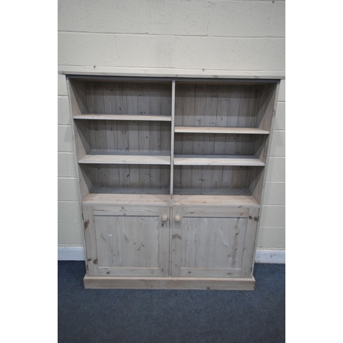 1248 - A MODERN LIMED PINE OPEN BOOKCASE, with two shelves within two division over double cupboard doors w... 