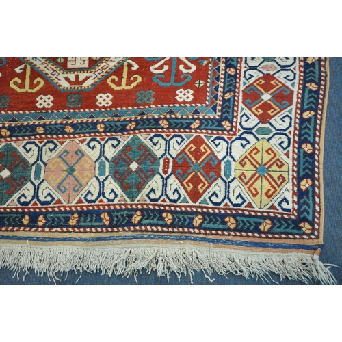 1297 - A LATE 19TH/EARLY 20TH CENTURY KAZAK WOOLLEN RUG, with a central medallion, red field, and a multist... 