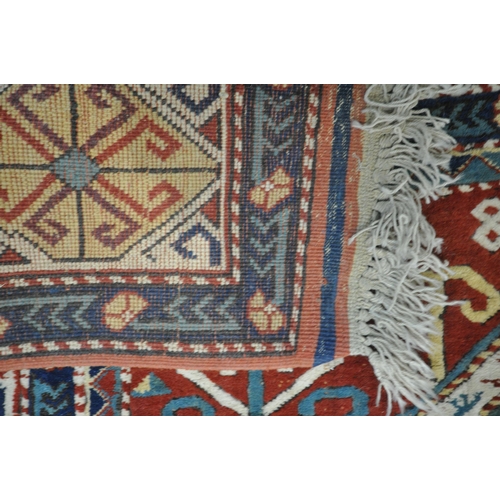 1297 - A LATE 19TH/EARLY 20TH CENTURY KAZAK WOOLLEN RUG, with a central medallion, red field, and a multist... 