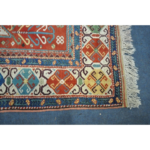 1299 - A LATE 19TH/EARLY 20TH CENTURY KAZAK WOOLLEN RUG, with a central medallions, red field, and multistr... 