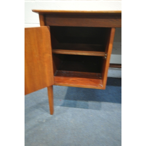 1309 - IN THE MANNER OF GORDON RUSSELL, a mid-century teak desk, with a single cupboard door, and three dra... 