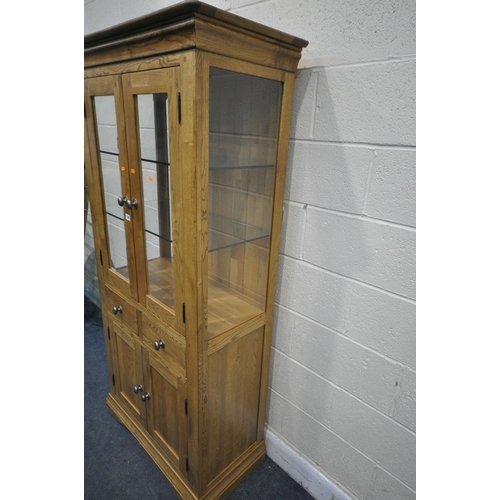 1330 - A SOLID OAK GLAZED CABINET, with two glass shelves and a two drawers over two cupboard doors, width ... 