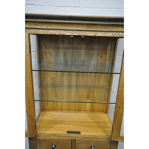 1330 - A SOLID OAK GLAZED CABINET, with two glass shelves and a two drawers over two cupboard doors, width ... 