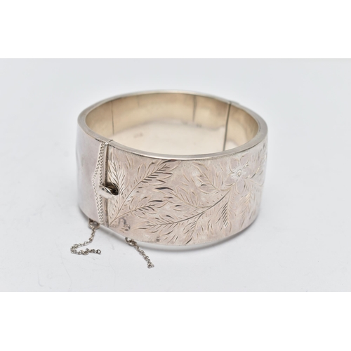 58 - A SILVER HINGED BANGLE, a wide bangle engraved with a floral and foliage design, approximate width 3... 