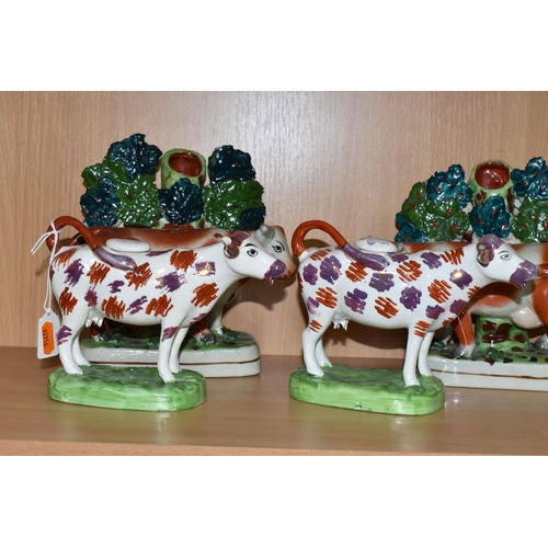 378 - FOUR PIECES OF COW THEMED POTTERY, comprising two cow creamers with red and pink lustre patches, sta... 