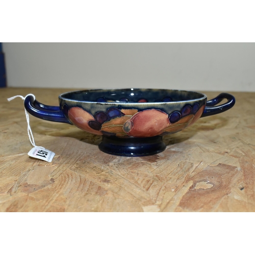 451 - A WILLIAM MOORCROFT TWIN HANDLED FOOTED BOWL DECORATED WITH POMEGRANATE PATTERN ON A DARK BLUE MOTTL... 