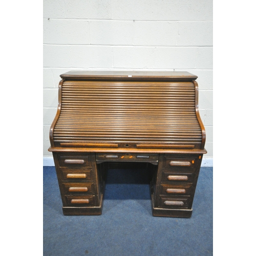 1216 - AN EARLY 20TH CENTURY OAK ROLL TOP DESK, enclosing an arrangement of shelving and two drawers, over ... 