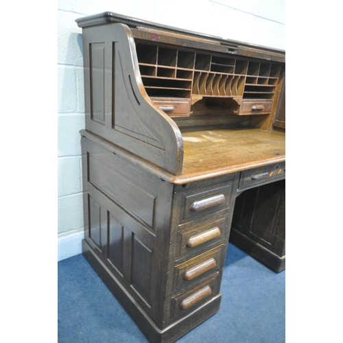 1216 - AN EARLY 20TH CENTURY OAK ROLL TOP DESK, enclosing an arrangement of shelving and two drawers, over ... 