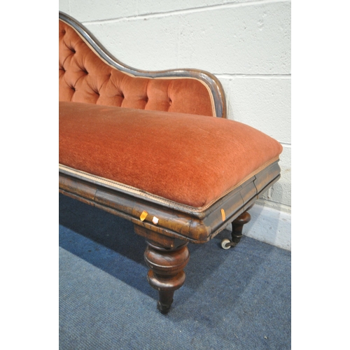 1252 - A VICTORIAN MAHOGANY CHAISE LONGUE, with red buttoned fabric, on turned legs and ceramic casters, Le... 