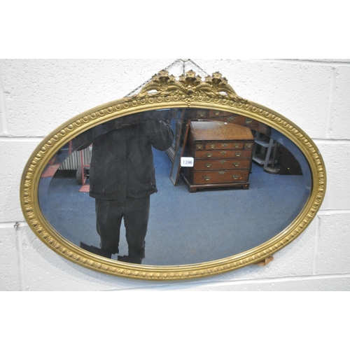 1392 - A 19TH CENTURY OVAL GILTWOOD WALL MIRROR, with a floral pediment and bevelled  edged plate 84cm x 58... 