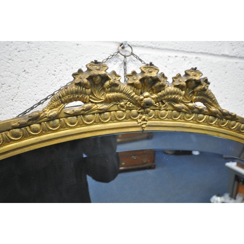 1392 - A 19TH CENTURY OVAL GILTWOOD WALL MIRROR, with a floral pediment and bevelled  edged plate 84cm x 58... 