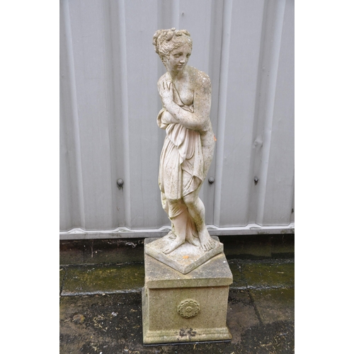 1010 - A WEATHERED COMPOSITE GARDEN FIGRURE OF A SCANTILY CLAD WOMAN on a square base measuring width 30cm ... 