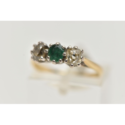 38 - A YELLOW  METAL EMERALD AND DIAMOND THREE STONE RING, centring on an oval cut emerald, flanked with ... 