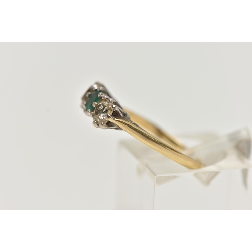 38 - A YELLOW  METAL EMERALD AND DIAMOND THREE STONE RING, centring on an oval cut emerald, flanked with ... 