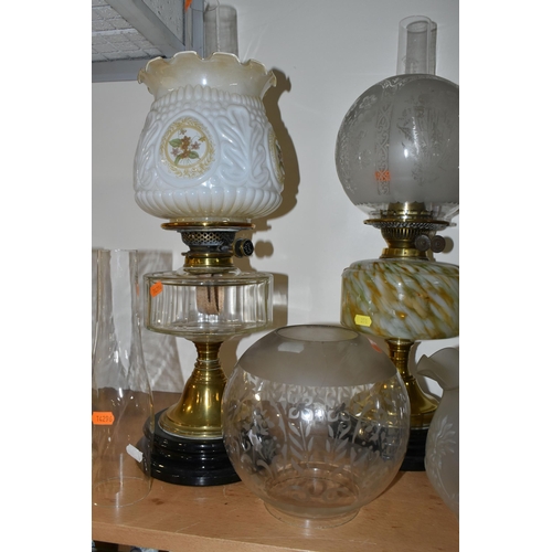 351 - THREE OIL LAMPS AND A SELECTION OF SHADES, the oil lamps all having glass reservoirs - one with gree... 