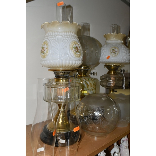 351 - THREE OIL LAMPS AND A SELECTION OF SHADES, the oil lamps all having glass reservoirs - one with gree... 