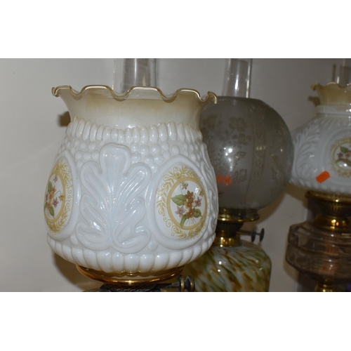 351 - THREE OIL LAMPS AND A SELECTION OF SHADES, the oil lamps all having glass reservoirs - one with gree... 