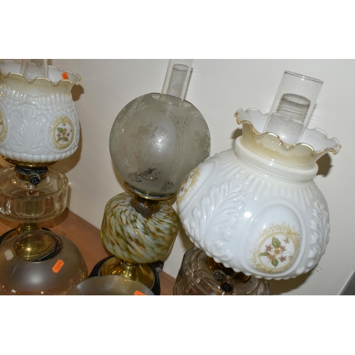 351 - THREE OIL LAMPS AND A SELECTION OF SHADES, the oil lamps all having glass reservoirs - one with gree... 