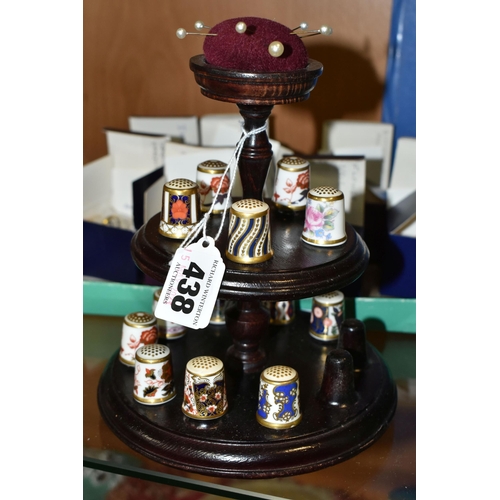 438 - A COLLECTION OF ROYAL CROWN DERBY THIMBLES, comprising fifteen boxed thimbles, and a wooden stand wi... 