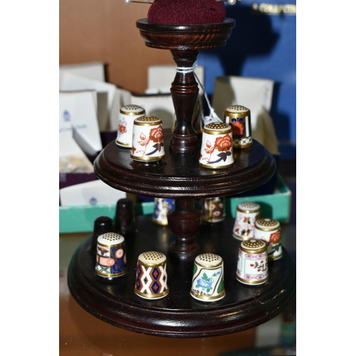 438 - A COLLECTION OF ROYAL CROWN DERBY THIMBLES, comprising fifteen boxed thimbles, and a wooden stand wi... 