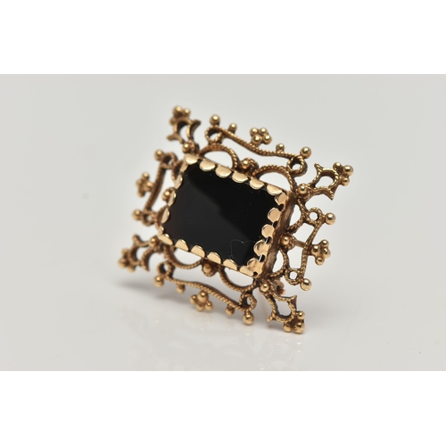 123 - A YELLOW METAL ONYX BROOCH PENDANT, a rectangular cut onyx set within an open work and beaded design... 