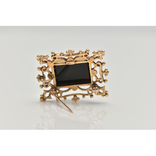 123 - A YELLOW METAL ONYX BROOCH PENDANT, a rectangular cut onyx set within an open work and beaded design... 