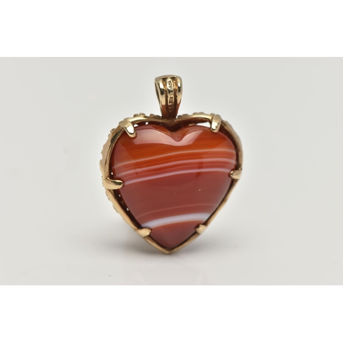 131 - A 9CT GOLD BANDED AGATE HEART PENDANT, polished orange and white agate heart within a floral detaile... 