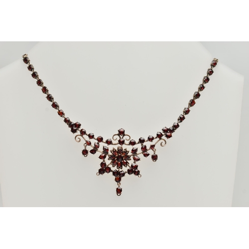 135 - A BOHEMIAN GARNET FESTOON STYLE NECKLACE, rose metal set with a cluster of circular cut garnets, lea... 